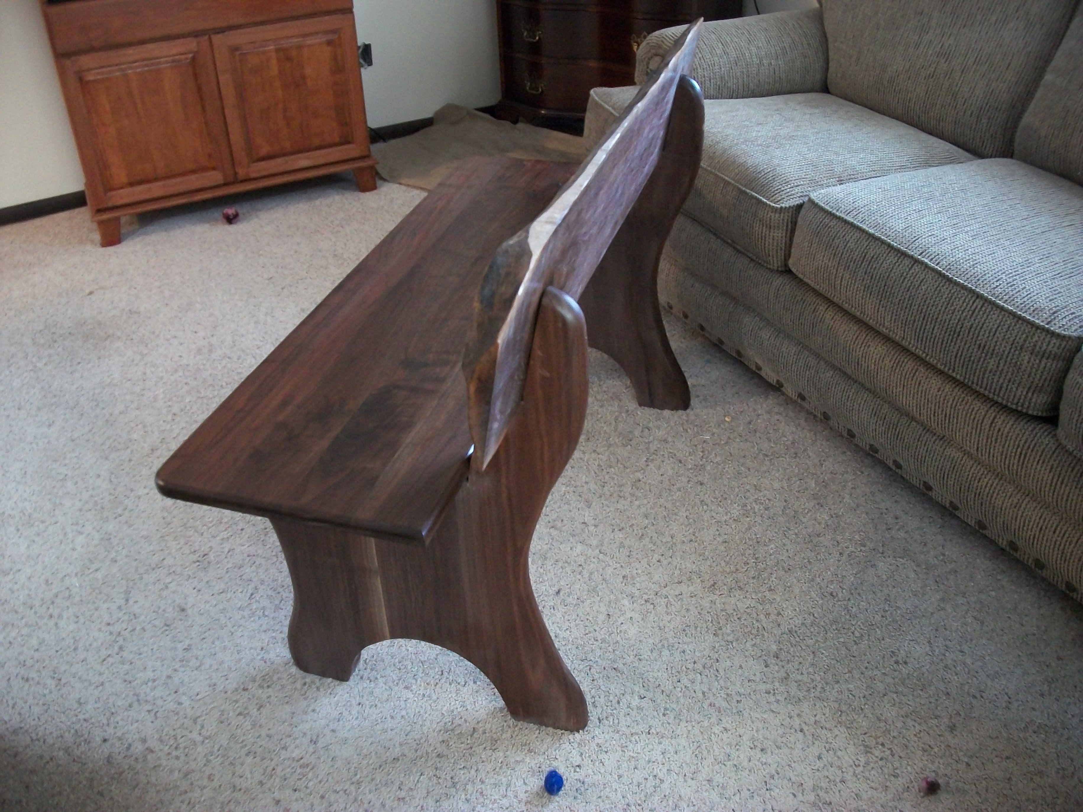 View of the bench from the side showing the curve of the legs and back support.