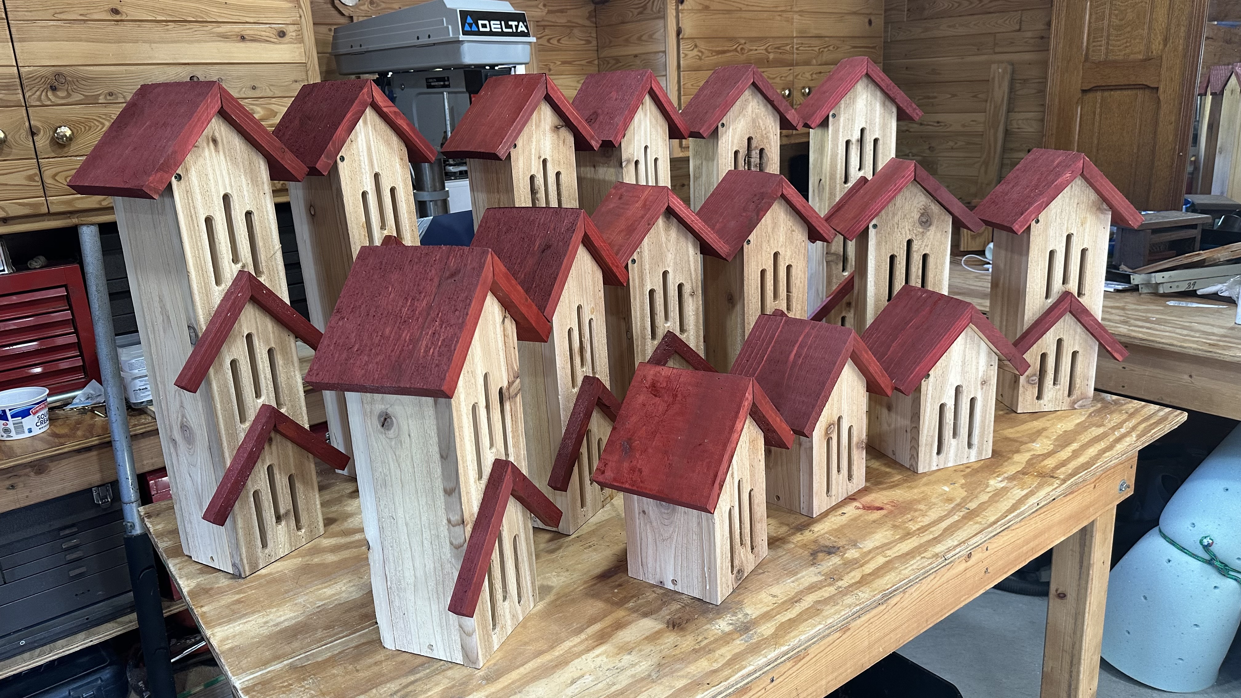 Photo of 15 butterfly houses. 6 3-tier,, 6 two-tear, and three single tier .All made of natural cedar and the roof pieces are red barn stained.